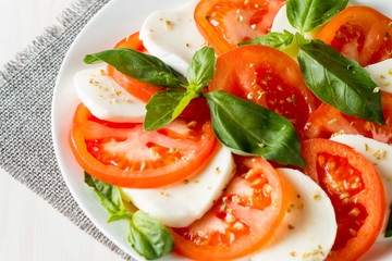 Close-up photo of caprese salad with ripe tomatoes, basil, buffalo mozzarella cheese. Italian and Mediterranean food concept. Fresh and healthy organic meal. Starter and antipasti.
