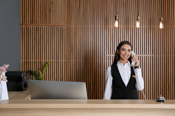 Receptionist talking on phone at desk in lobby