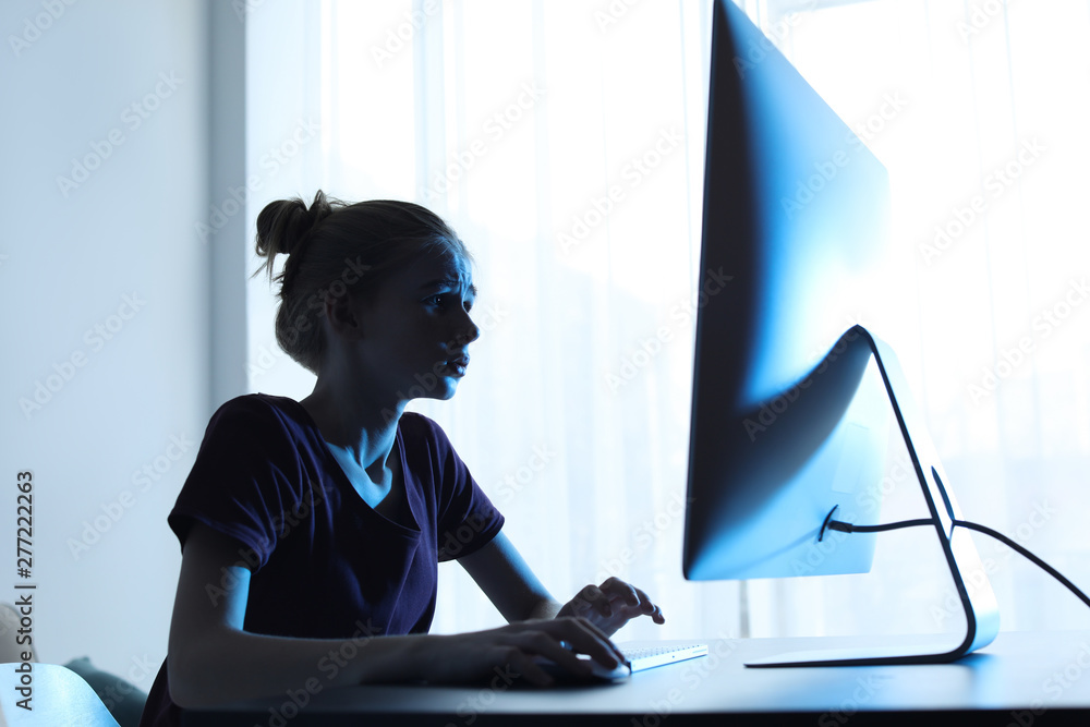 Wall mural shocked teenage girl using computer at table indoors. danger of internet