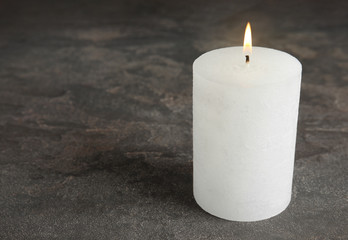 Alight wax candle on grey background. Space for text