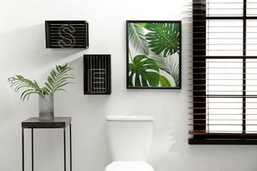Table with vase and shelves near toilet bowl in restroom interior