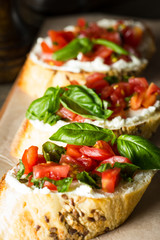 Tomato and cheese fresh made bruschetta. Italian tapas, antipasti with vegetables, herbs and oil on grilled ciabatta and baguette bread.