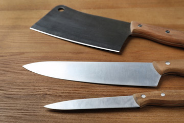 Set of sharp kitchen knives on wooden table