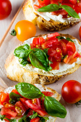 Tomato and cheese fresh made bruschetta. Italian tapas, antipasti with vegetables, herbs and oil on grilled ciabatta and baguette bread.