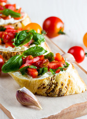Tomato and cheese fresh made bruschetta. Italian tapas, antipasti with vegetables, herbs and oil on grilled ciabatta and baguette bread.