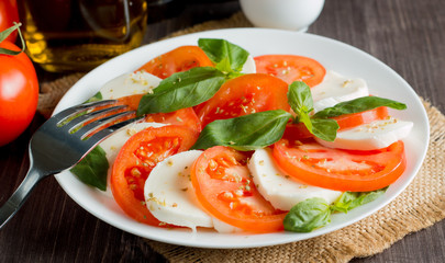 Close-up photo of caprese salad with ripe tomatoes, basil, buffalo mozzarella cheese. Italian and Mediterranean food concept. Fresh and healthy organic meal. Starter and antipasti.