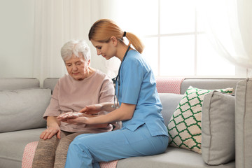 Nurse with elderly woman indoors. Assisting senior people