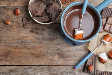 Flat lay composition with chocolate fondue and space for text on wooden background