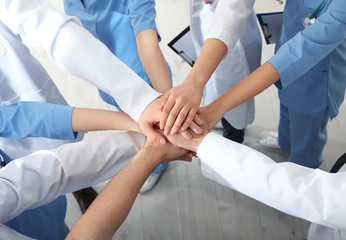 Team of medical workers holding hands together indoors, above view. Unity concept