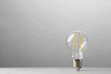 Vintage lamp bulb on light table against grey background. Space for text