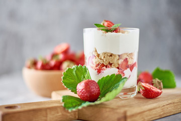 Smoothie with summer strawberry in glass jar and fresh berries  in wooden bowl on a gray background