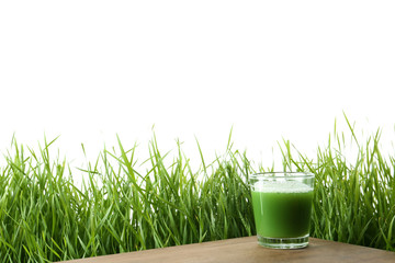 Glass of juice on table and fresh wheat grass against white background. Space for text