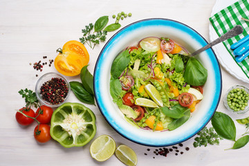 Healthy vegan dietary salad. Tomato, cucumber, avocado, purple onion, lettuce, basil leaves, seasoned with olive oil and lime juice. Summer menu.