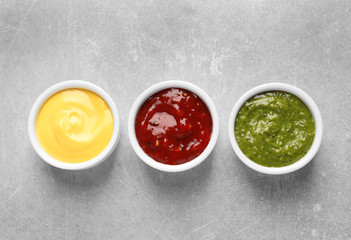Set of different delicious sauces on grey table, top view