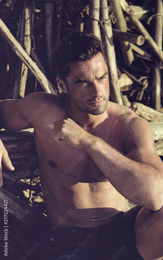 Wall mural Portrait of a handsome, muscular man relaxing on a tropical beach