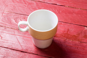 Empty cup on claret color wooden background.