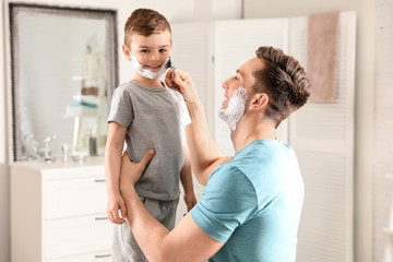 Obraz premium Dad pretending to shave his little son in bathroom