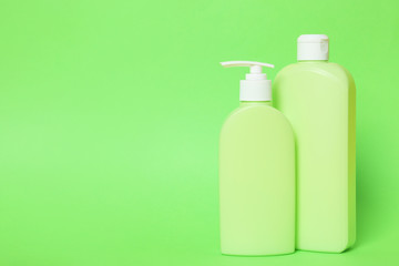 Bottles of shampoo on green background, space for text. Natural cosmetic products