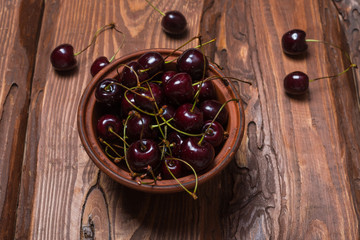 Fresh sweet sweet cherry in a plate on a wooden background.