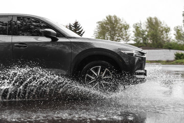 Modern car driving outdoors on rainy day