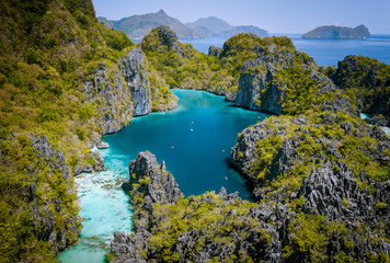El Nido, Palawan, Philippines. Aerial drone view of beautiful big lagoon surrounded by karst limestone cliffs. Tourists explore area on kayaks