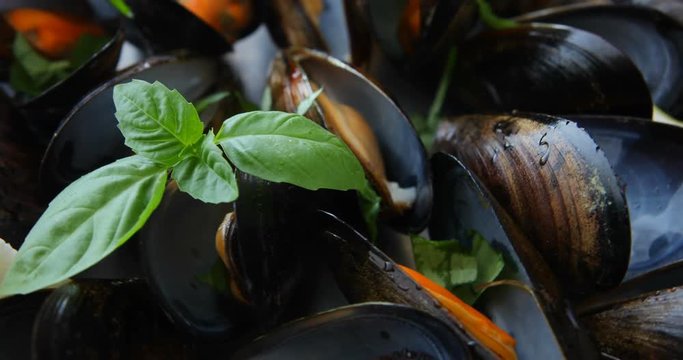 Shellfish mussels in copper bowl with lemon and herbs on white background with textile rotation 360. Shellfish seafood close-up.