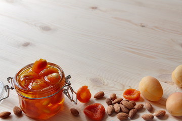 Jar of homemade sugar-free fruit confiture jam or honey with dried and raw apricots and nuts wooden table background with copy space