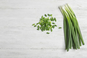 Cut and fresh green onions on white wooden table, flat lay with space for text
