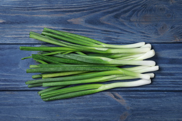 Fresh green onions on blue wooden background, top view