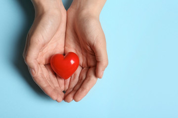 Woman holding heart on blue background, top view with space for text. Donation concept