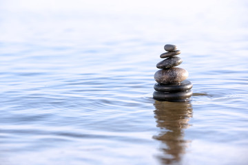 Stack of dark stones in sea water, space for text. Zen concept