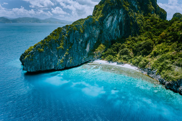 Aerial drone view of tropical Entalula Island. Huge steep rocks cliffs mountains surrounding blue...