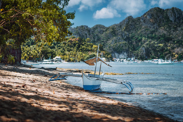 Bangka fishing boat on shore with El Nido village in background, Palawan, Philippines