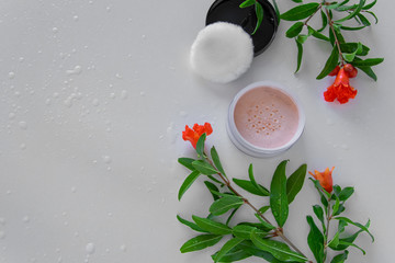 Top view of botanical face powder with blossom pomegranate branch. Herbal cosmetics