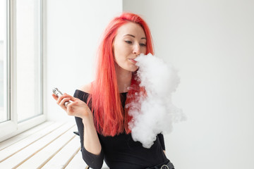 Vape, addiction and people concept - young woman with colored hair is smoking a vape