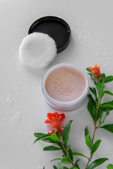 Top view of botanical face powder with blossom pomegranate branch. Herbal cosmetics