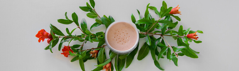 Top view of botanical face powder with blossom pomegranate branch. Herbal cosmetics