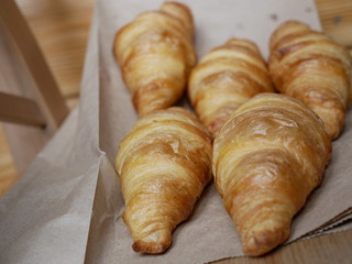five fresh croissants lying on a package from the bakery. delicious pastries