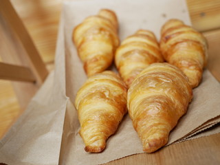 five fresh croissants lying on a package from the bakery. delicious pastries