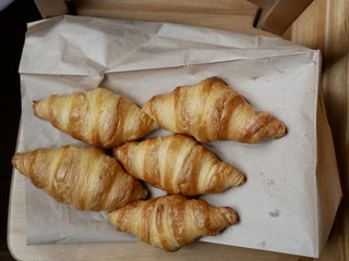 five fresh croissants lying on a package from the bakery. delicious pastries