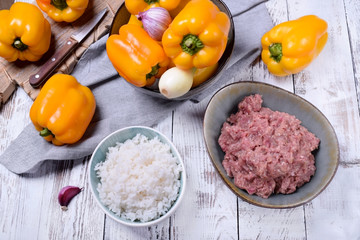Boiled rice, raw pork and beef mince and yellow bell peppers. Ingredients for making stuffed peppers