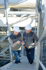 male workers in hardhat standing on steel staircase