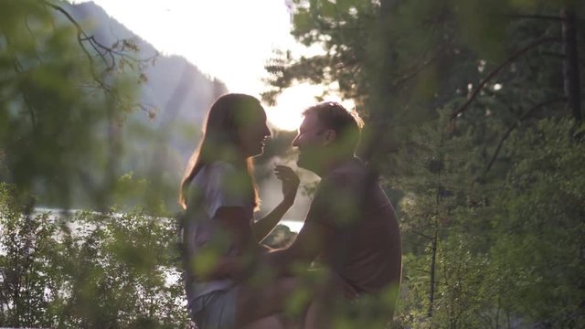 Couple in love kisses at sunset. Romantic date men and women in the summer in the Altai Mountains. The woman sits on a man and they gently kiss and laugh. Husband and wife love each other