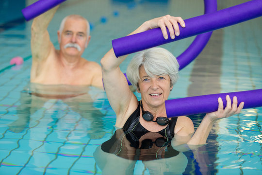 Senior People Exercising With Floats In Swimming Pool