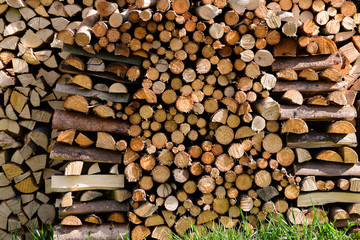 Wall of stacked wood logs as background. Pile of wood logs ready for winter. Wooden stumps, texture background. Firewood stacked and prepared for winter. Woodpile.