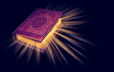 Old magic book with light rays isolated on black background.
