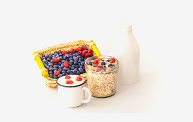 Muesli with blueberries and raspberries in glass jar on white background. 