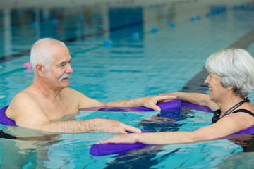 elderly couple doing exercise movement in swimming pool