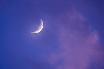 Obraz na płótnie Canvas Crescent moon through purple sunset clouds