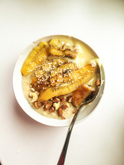 Breakfast oatmeal porridge with chia seeds, nuts, sesame, soy yogurt and banana with a metal spoon. Proper vegetarian breakfast instagram style top view